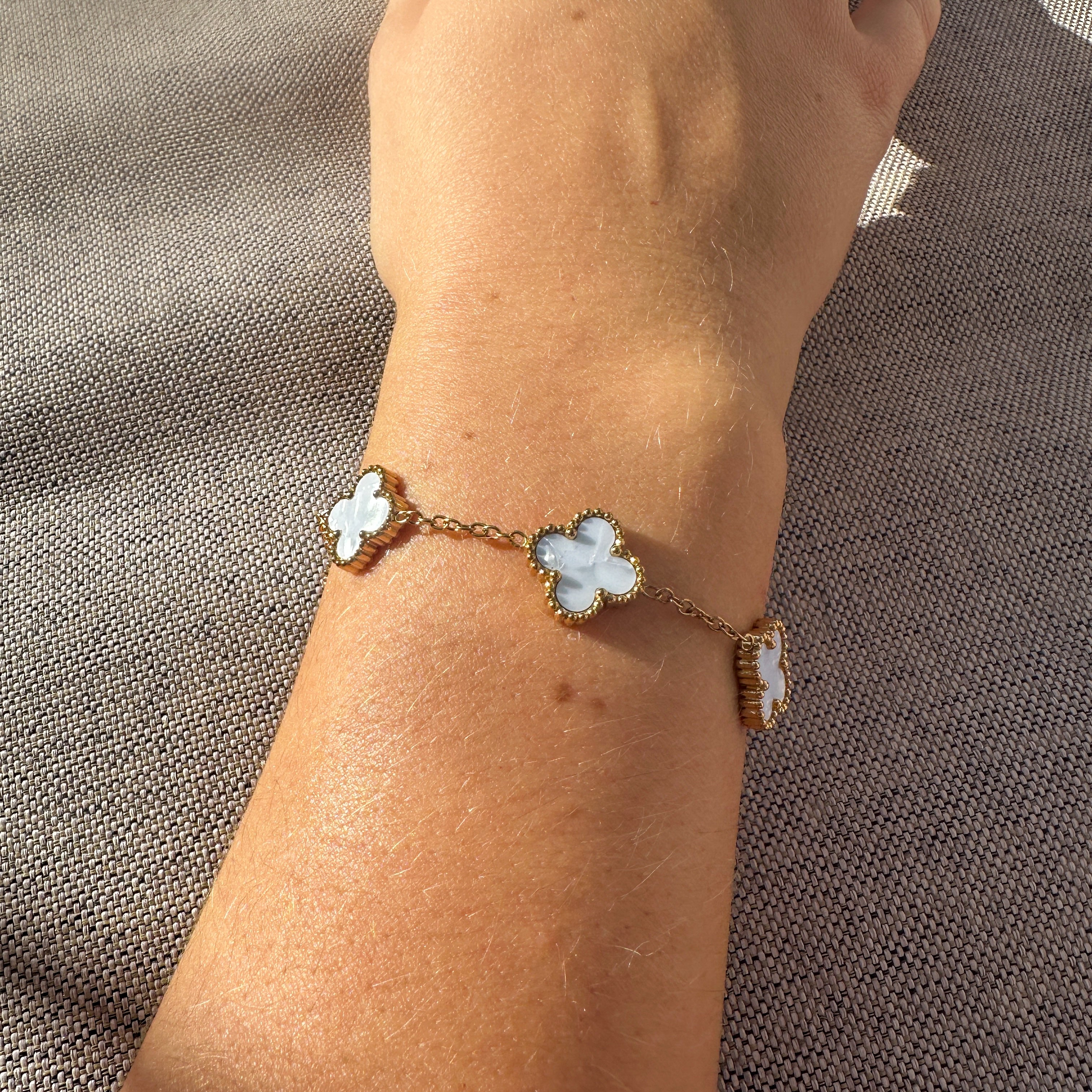 Bracelet with flower-shaped charms on a wrist against a textured brown background
